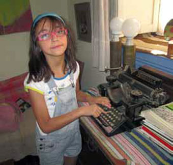 Florencia, 10 años, junto a la máquina de escribir de Eduardo Barrios.
